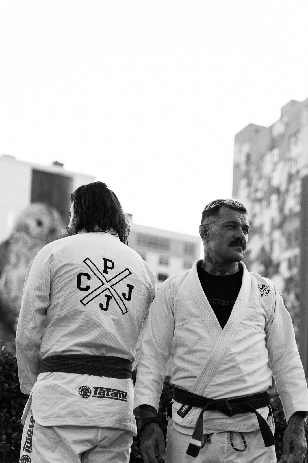 Two Constant Pressure Jiu Jitsu athletes wearing white gis outdoors